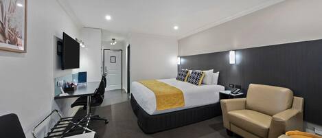 Una habitación de hotel con cama, escritorio, silla y televisor.