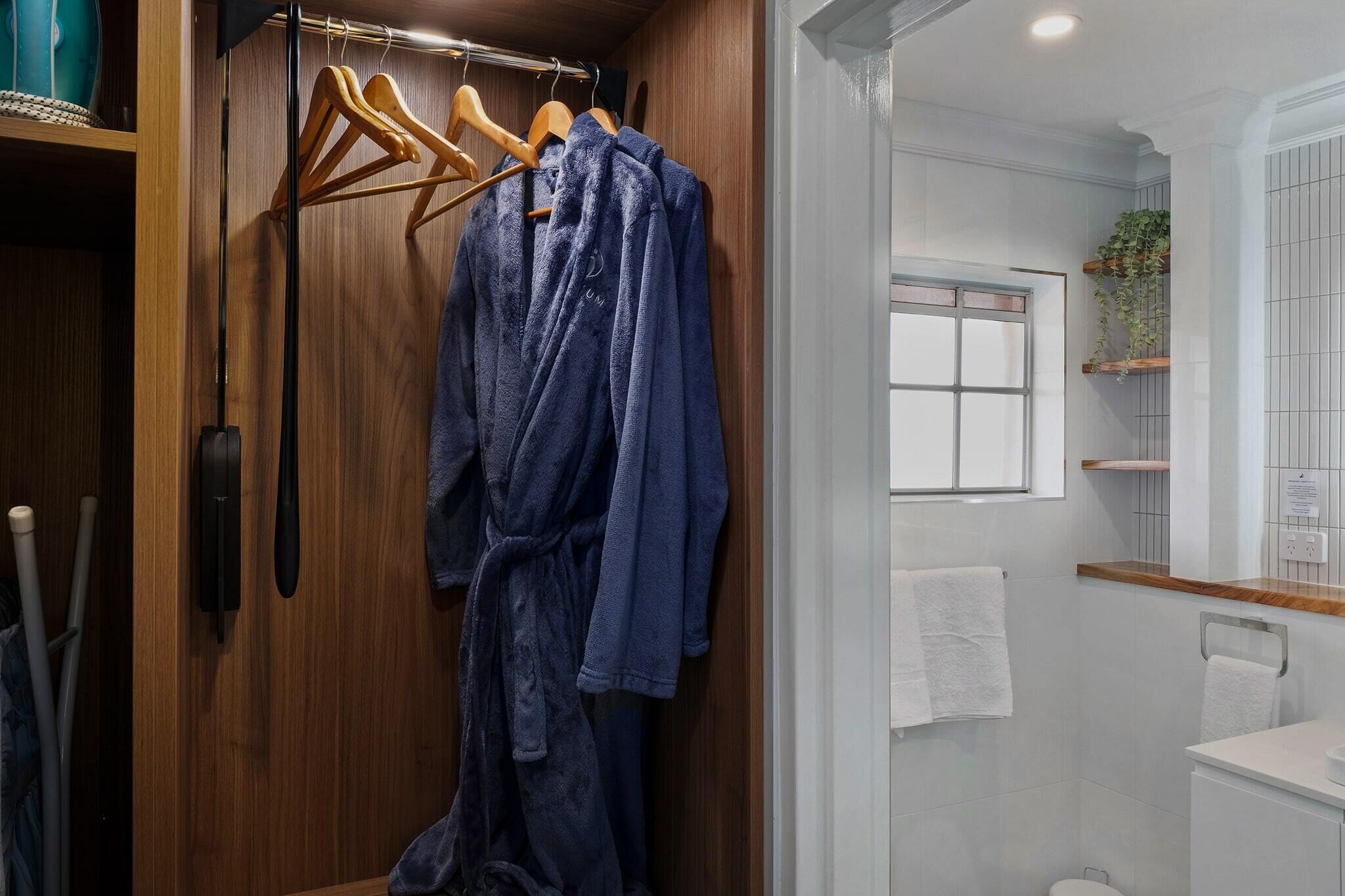 A bathroom with a wooden vanity, a towel rack, and a window.