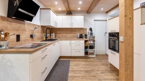 A modern kitchen with white cabinets, wooden countertops, and a built-in oven.
