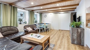Un salon chaleureux avec un canapé en cuir, une table basse en bois et un coin repas comprenant une table et des chaises.