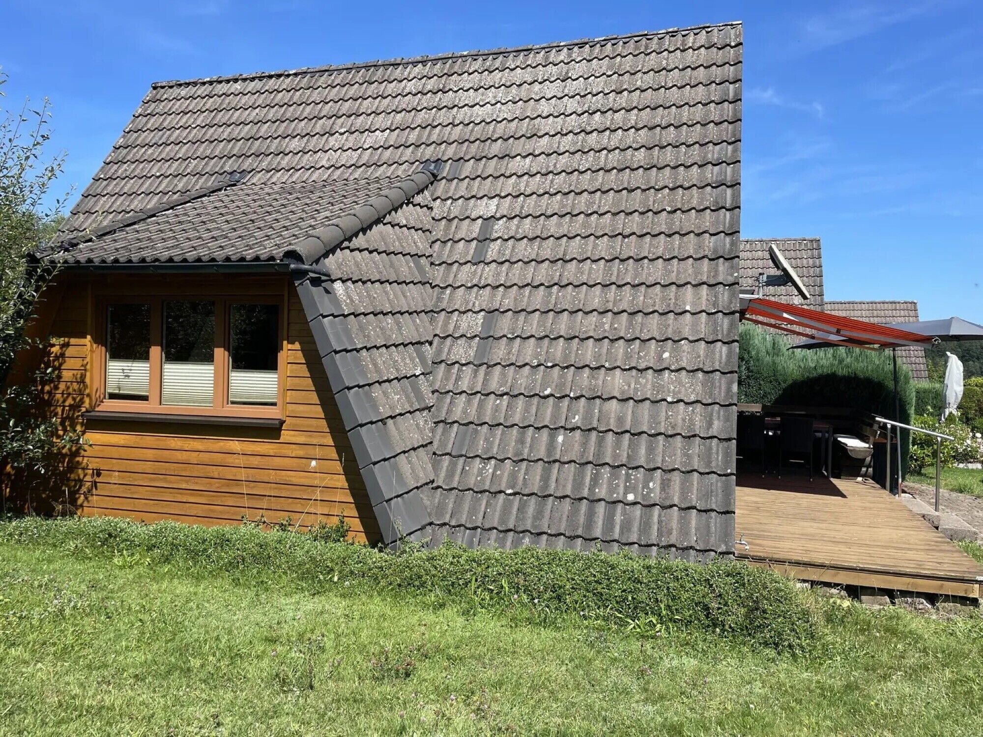 A wooden cabin with a sloped roof, a window, and a deck.