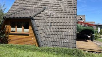 A wooden cabin with a sloped roof, a window, and a deck.