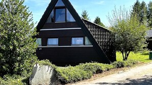 Ein schwarzes, dreieckiges Haus mit einem großen Fenster und einem kleineren Fenster an der Seite.