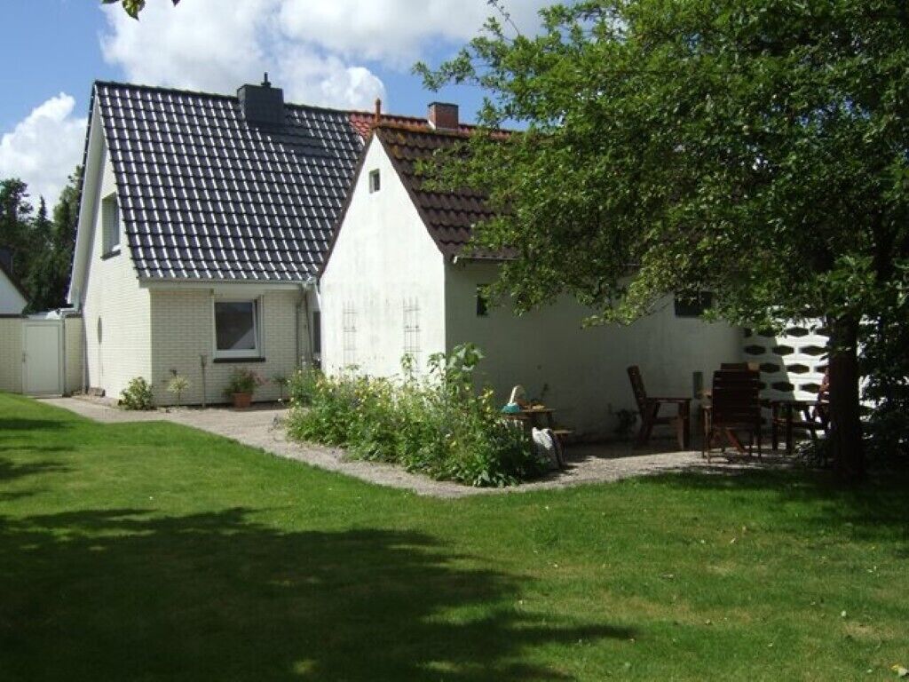 Une maison de plain-pied avec un toit en tuiles, un petit porche à l’avant et une pelouse bien entretenue.