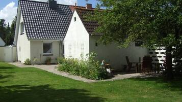Une maison de plain-pied avec un toit en tuiles, un petit porche à l’avant et une pelouse bien entretenue.