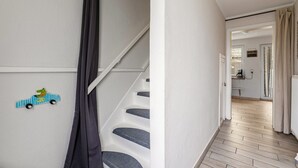 A staircase with grey steps, a wall-mounted light switch, and a small wall decoration of a car. - Holiday Home 'Nilsson' with Private Terrace, Private Garden and Wi-Fi (Heide)