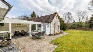 A house with an attached patio area, a dining table, chairs, and a small garden. - Holiday Home 'Nilsson' with Private Terrace, Private Garden and Wi-Fi (Heide)