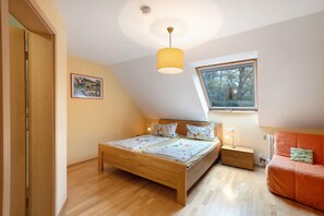 A bedroom with a wooden bed, a nightstand, a lamp, a window, and a view of trees.