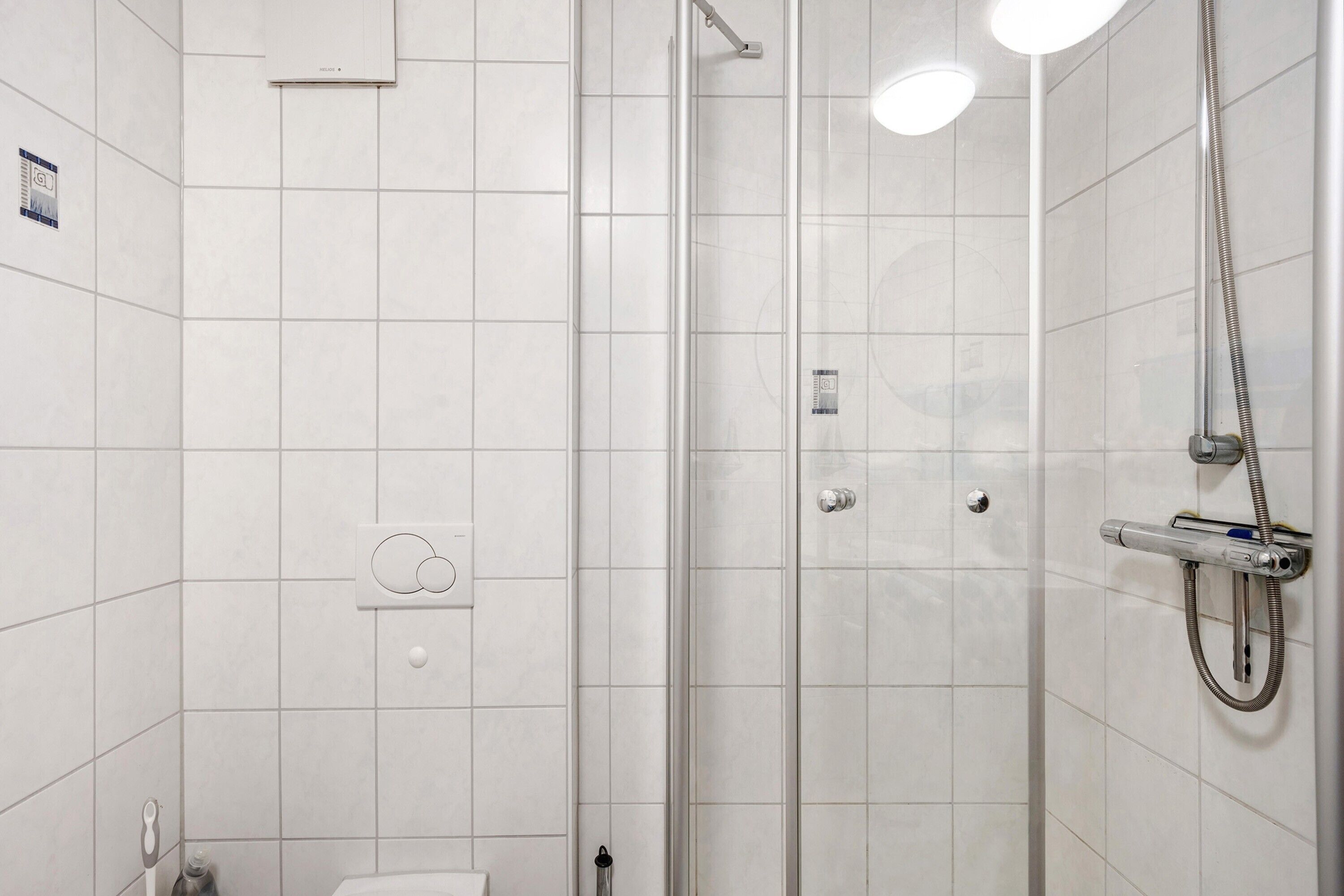 A modern bathroom with a glass shower enclosure, a toilet, and a towel rack.