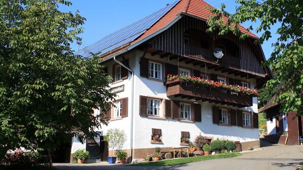 A traditional chalet with a sloped roof, wooden balconies, and flower boxes.