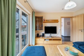 Un salon moderne avec un téléviseur, des meubles en bois, un canapé et un coin repas avec une table.