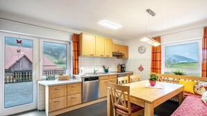 Une cuisine moderne avec des meubles en bois, un lave-vaisselle et un coin repas comprenant une table et des chaises.