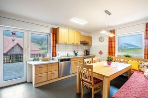 A modern kitchen with wooden cabinets, a dishwasher, and a dining area with a table and chairs.