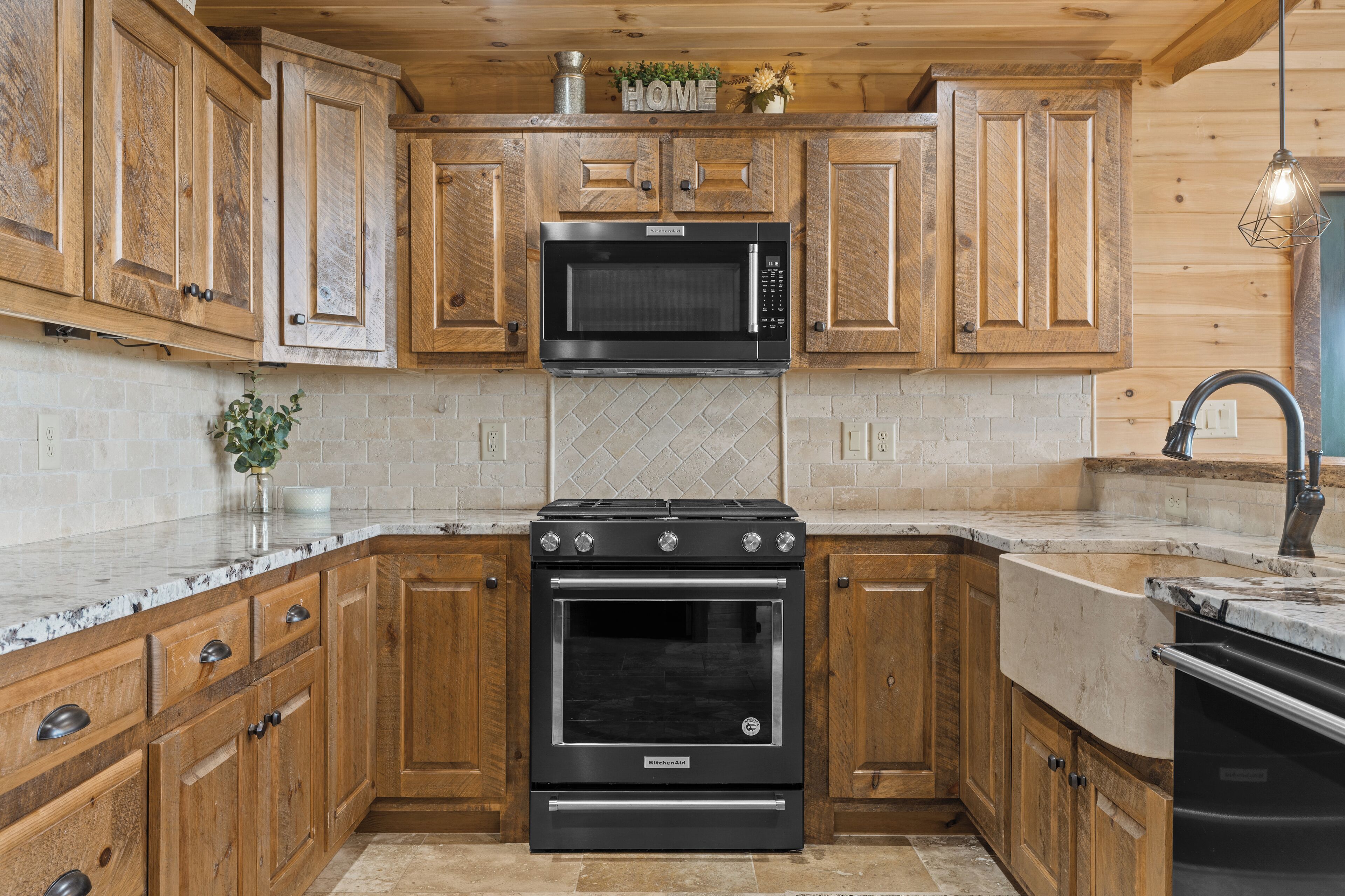 A kitchen with wooden cabinets, a black microwave, a stove, and a dishwasher.