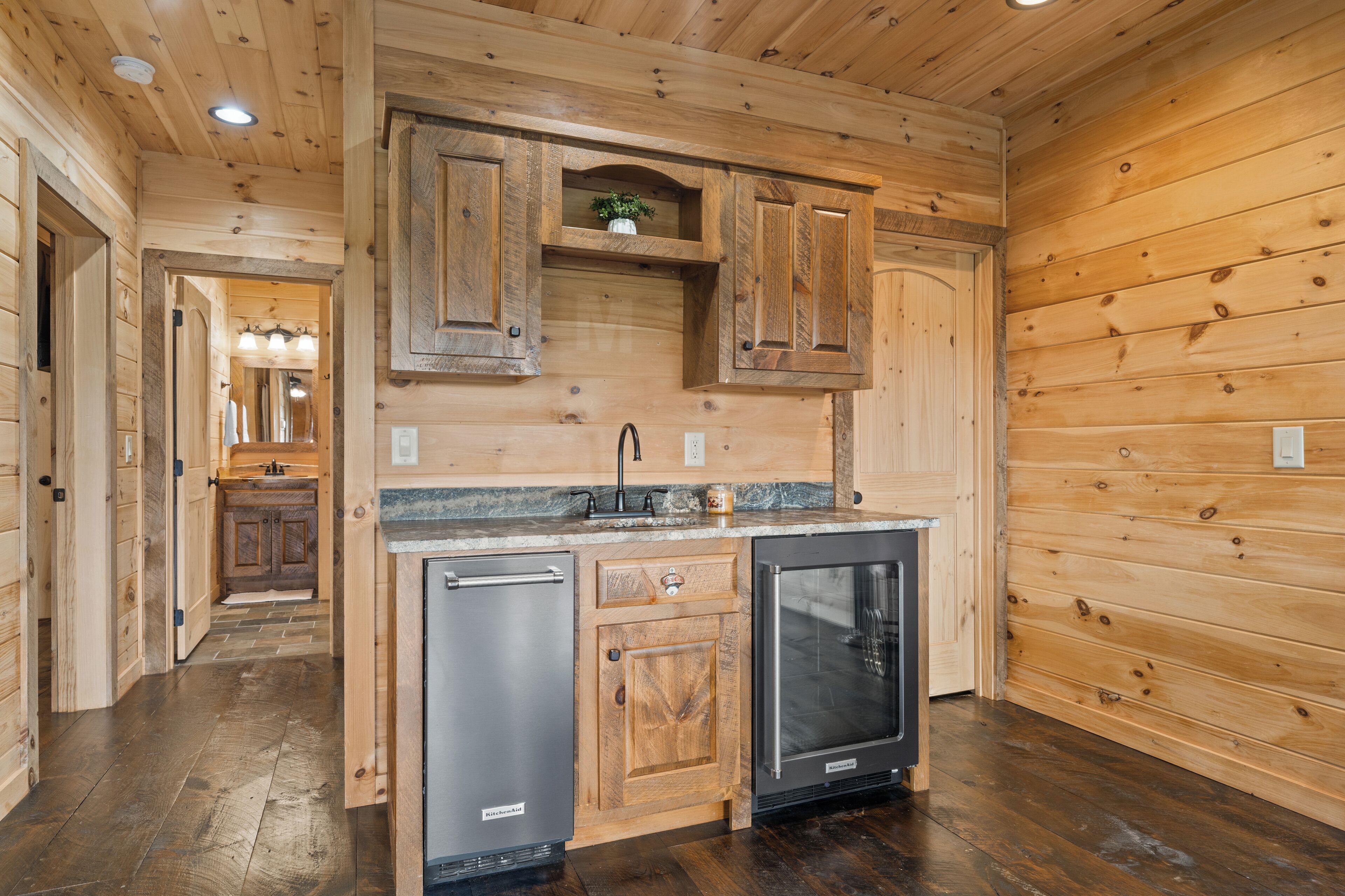 A wooden interior with a kitchen area featuring cabinets, a refrigerator, and a dishwasher.