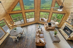 A cabin with a wooden interior, large windows, a fireplace, and a deck with outdoor furniture. - Serenity View (Blue Ridge)