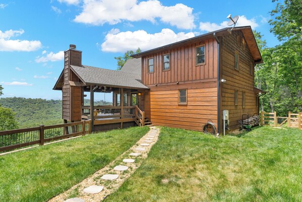 A wooden cabin with a porch, stone pathway, and a scenic view.