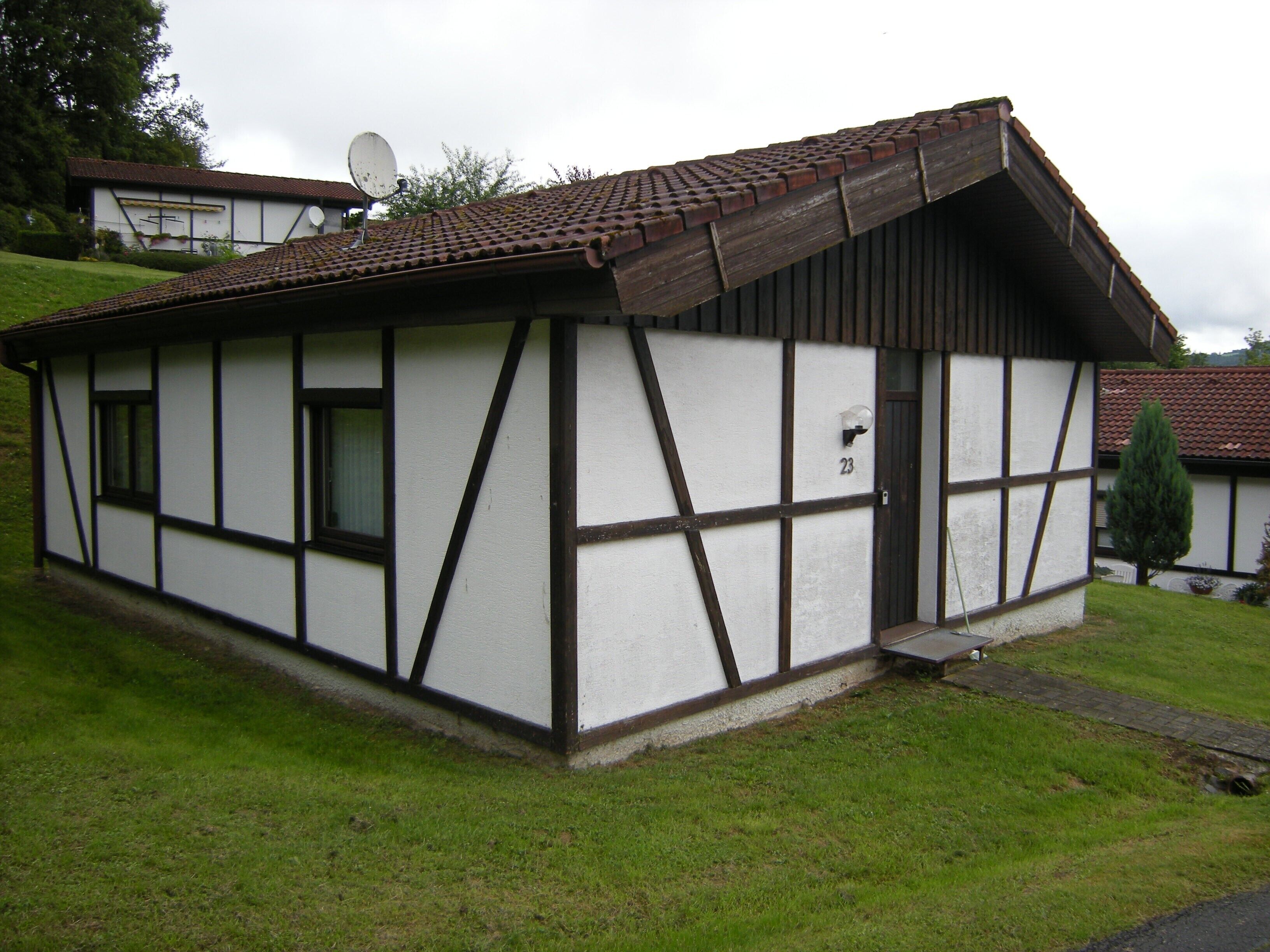 Un petit bâtiment d’un seul étage, doté d’un toit en pente, d’une porte bien visible et d’une antenne parabolique sur le toit.