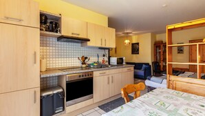 A compact kitchen with wooden cabinets, a microwave, and a sink. - Studio Apartment 'Gudrun' with Private Terrace, Shared Garden and Wi-Fi (Usingen)
