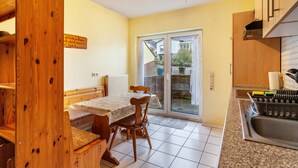 A kitchen with a dining table, chairs, a built-in oven, and a sliding glass door leading to an outdoor area. - Studio Apartment 'Gudrun' with Private Terrace, Shared Garden and Wi-Fi (Usingen)