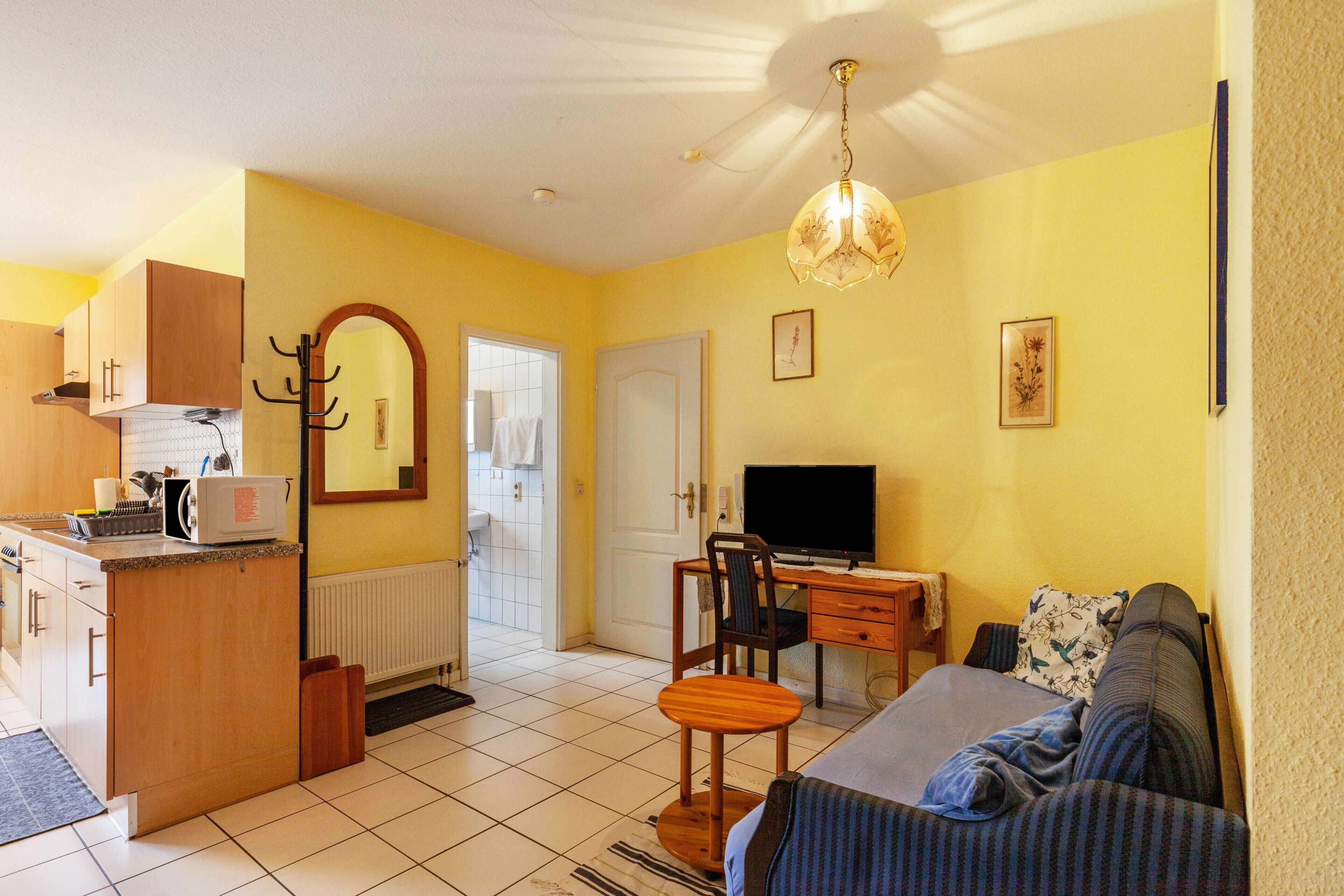 A compact living space with a kitchenette, a dining area, a television, and a sofa.