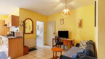 A compact living space with a kitchenette, a dining area, a television, and a sofa.