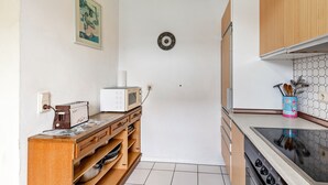A kitchen with wooden cabinets, a microwave, a coffee maker, and a sink. - Holiday Apartment 'Hildegard' with Shared Garden and Wi-Fi (Usingen)