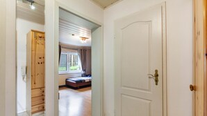 A hallway with a wooden wardrobe, a white door, and a room with a bed and window. - Holiday Apartment 'Hildegard' with Shared Garden and Wi-Fi (Usingen)