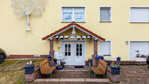 A building with a yellow facade, a white door with a red roof, and a tree sculpture on the wall. - Holiday Apartment 'Hildegard' with Shared Garden and Wi-Fi (Usingen)
