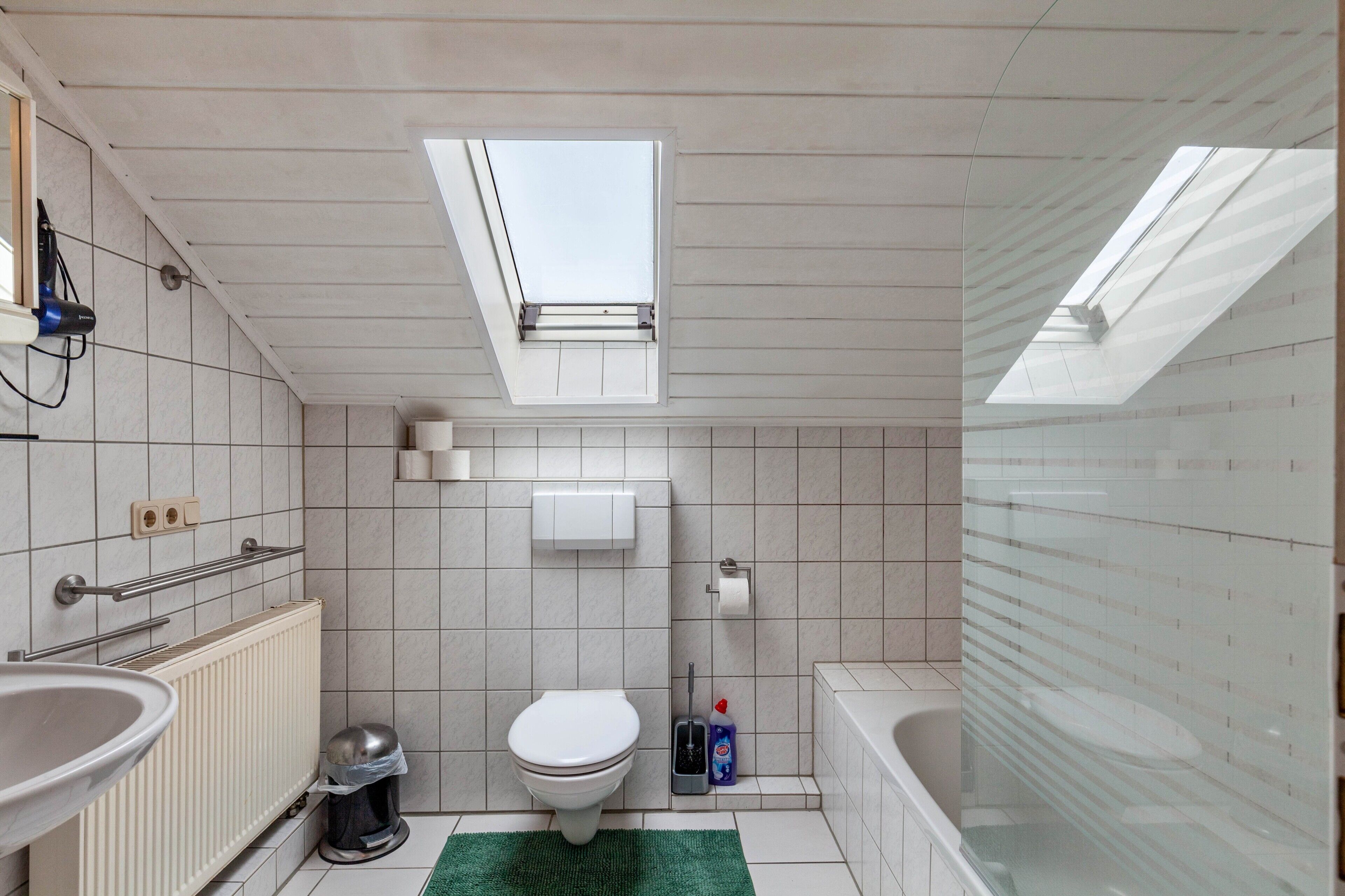 Bagno con finestra a lucernario, toilette, bidet, vasca e termosifone.