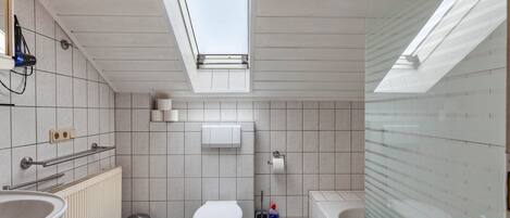 Bagno con finestra a lucernario, toilette, bidet, vasca e termosifone.