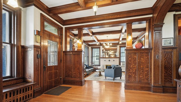 Ein geräumiges Foyer mit Holzboden, einer imposanten Treppe und einer Sitzecke mit Sofas.