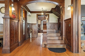 A grand wooden staircase with a black doormat at the base, leading to a second-floor landing.