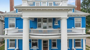 Ein zweistöckiges Haus mit einem Balkon im oberen Geschoss, einer Haustür und einer kleinen Veranda mit einem Stuhl.