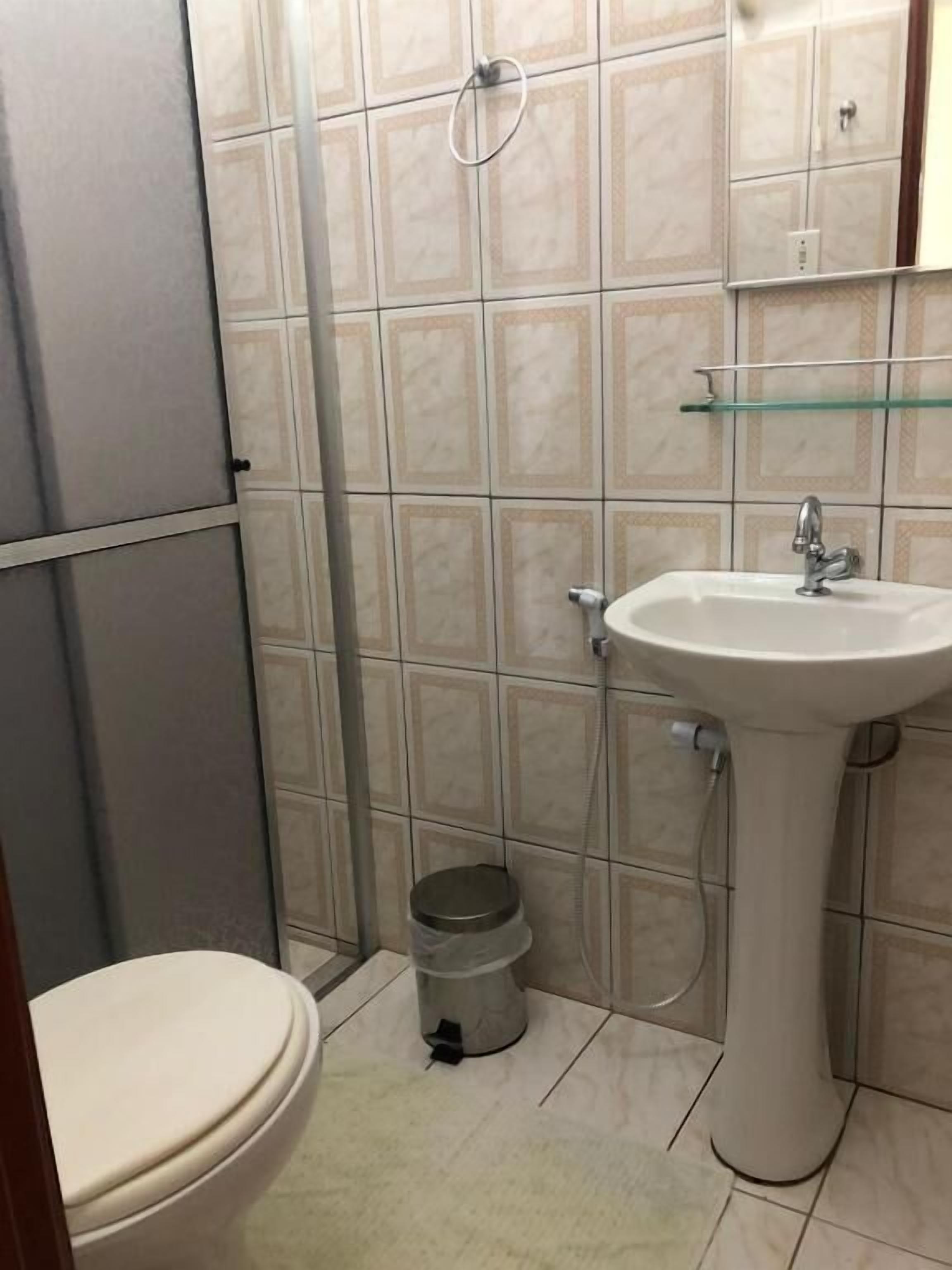 A small bathroom with a toilet, sink, and shower.
