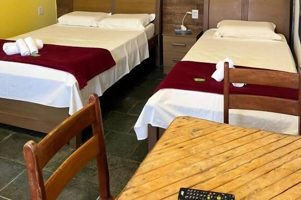 A hotel room with two beds, a wooden headboard, a small table, and a chair.