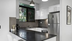 Una cucina moderna con un'isola grande, mobili bianchi, elettrodomestici in acciaio inossidabile e una finestra vista verde.
