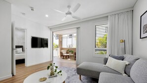 A modern living room with a grey sofa, a white coffee table, and a TV mounted on the wall.