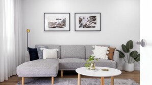 A modern living room with a grey sectional sofa, a round coffee table, and two framed pictures on the wall.
