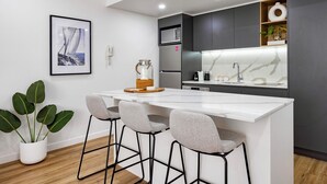 A modern kitchen with a white island, grey cabinets, and a marble backsplash.