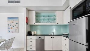 A modern kitchen with white cabinets, a stainless steel refrigerator, and a dishwasher.