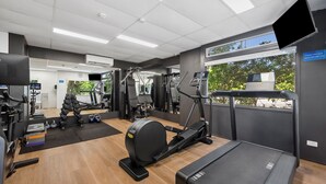 A gym with cardio machines, weightlifting equipment, and a treadmill.