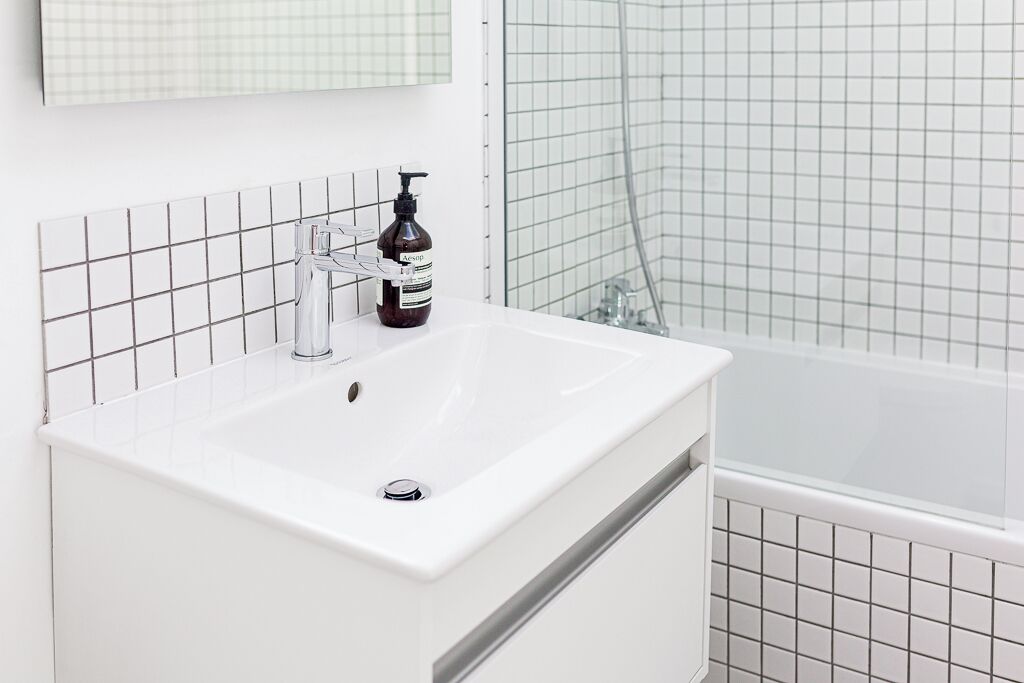 Une salle de bain avec un lavabo blanc, un miroir et un espace douche.