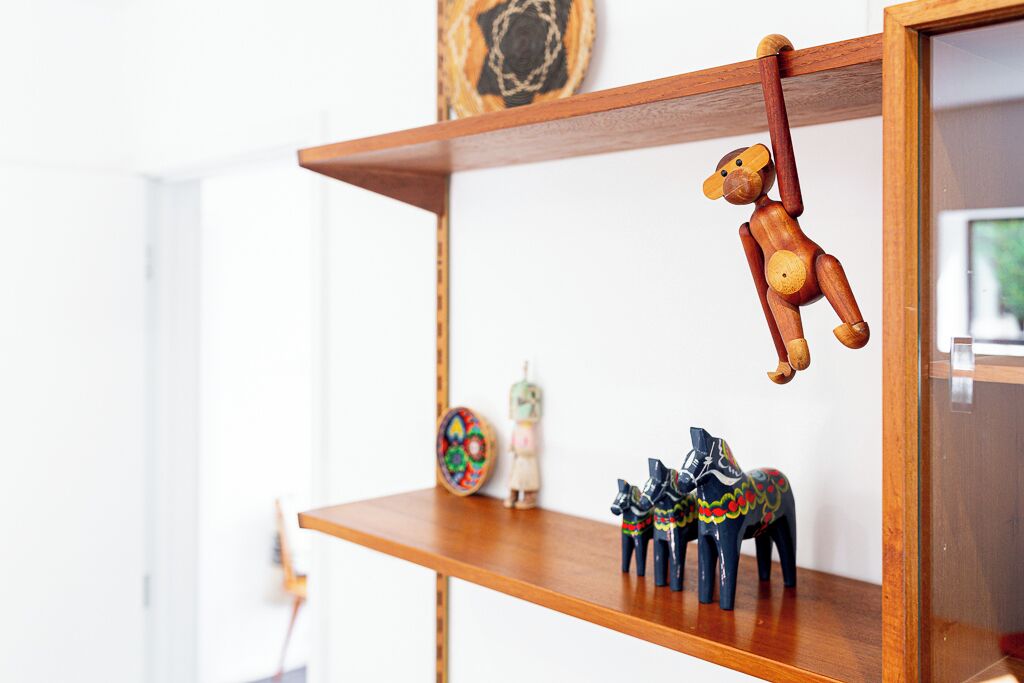 A wooden shelf with a hanging wooden figure and two painted horses.