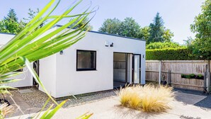A modern, single-story building with a flat roof, large windows, and a sliding glass door. - Mid-Century Modern Style 1BD with Garden (Cheltenham)