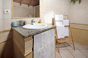 Une salle de bain équipée d’un lavabo, d’un miroir, d’un porte-serviettes et d’un porte-serviettes en bois.