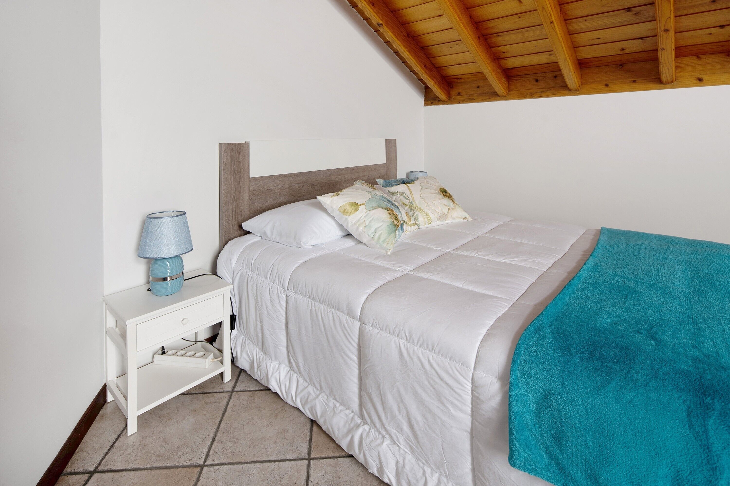 Una camera da letto con un letto, un comodino, una lampada e un soffitto in legno.