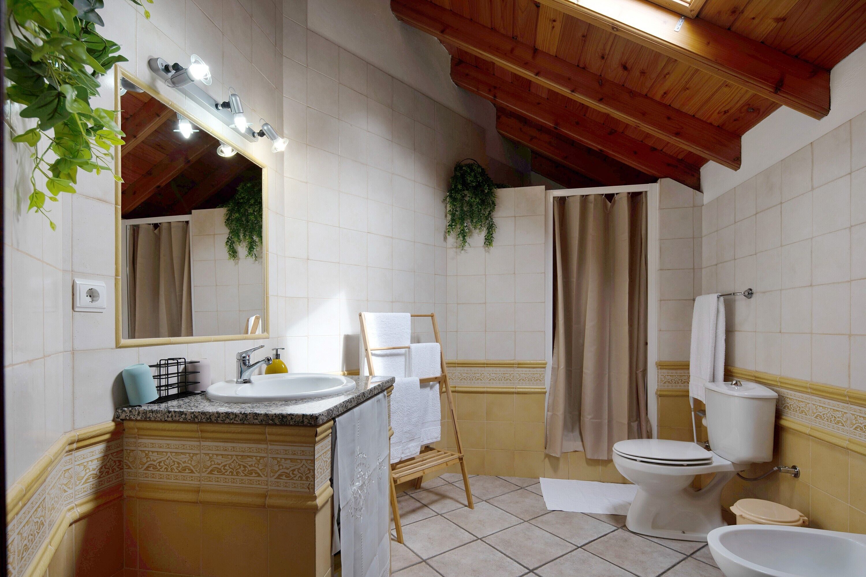 A bathroom with a sink, mirror, towel rack, toilet, and shower curtain.