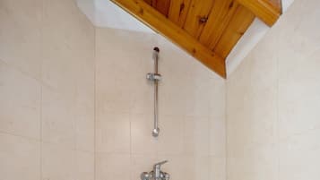 Una ducha con viga de madera en el techo, pared de azulejos y ducha de metal.