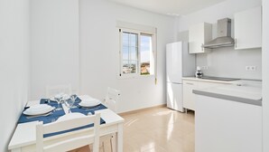 Moderni keittiö, jossa on valkoiset kaapit, sisäänrakennettu uuni ja ikkuna, josta avautuu näkymä kaupunkimaisemaan.